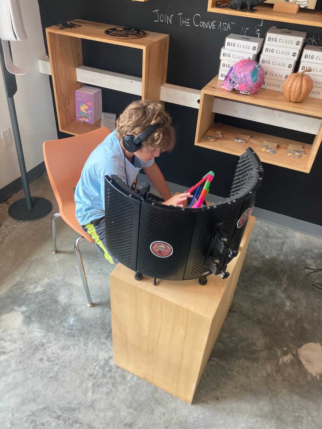 A young DJ recording inside a portable vocal booth with headphones on